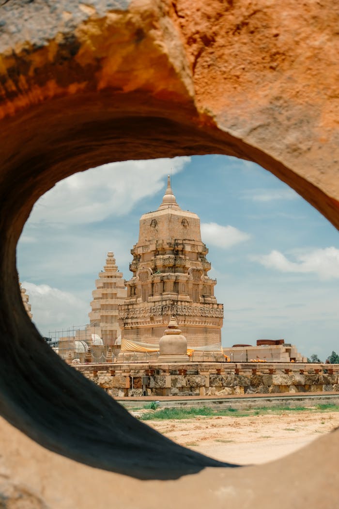 services-02 Explore the majestic view of an ancient Indian temple through a natural rock arch, showcasing historic architecture.